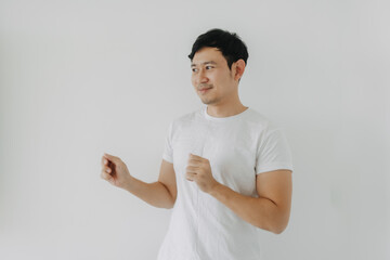 Happy asian bearded man rising his fist, happy fun dancing posing, looking at empty space and standing isolated over white background wall. 