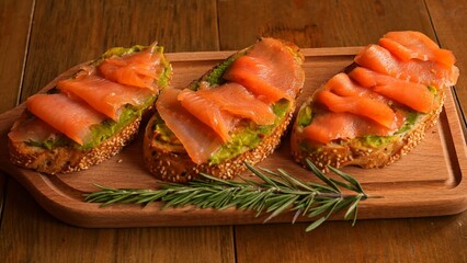 Slices of bread with red fish and avocado are presented on table Avocado nutrients complements savory red fish perfectly Enjoy delicious combination of red fish and avocado on bread slices