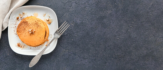 Plate of tasty pumpkin pancakes on dark grey background with space for text, top view