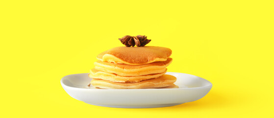 Plate of tasty pumpkin pancakes on yellow background