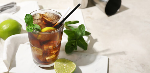 Glass of tasty Cuba Libre cocktail on light background with space for text