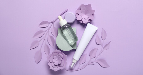 Natural cosmetic products with paper decor on lilac background