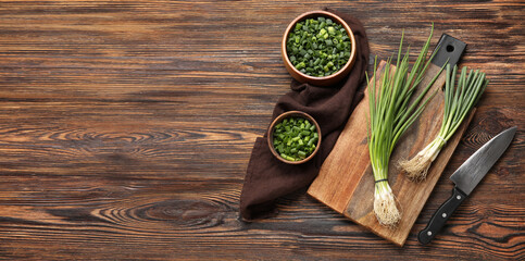 Cutting board with green onion and knife on wooden background with space for text
