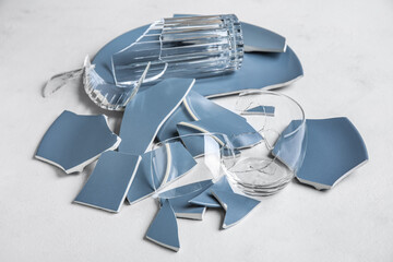 Broken plates and glasses on light background