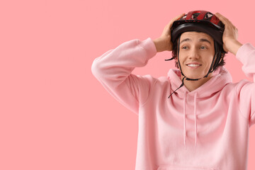 Young man in bike helmet on pink background