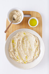 hummus on plate with olive oil on wooden cutting board