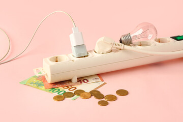 Power socket with money, light bulb and plugs on pink background. Electricity bill concept