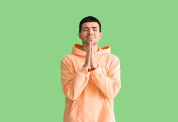 Fototapeta premium Young man praying on green background