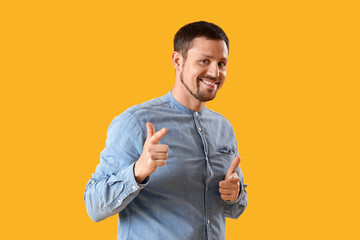 Handsome man pointing at viewer on yellow background
