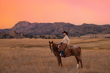 Wyoming Cowgirl portrait on horse with colorful sky