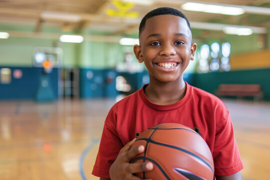 Portrait happy boy holding basketball in a school gymnasium