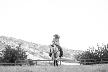 Fototapeta premium Cowgirl riding grey quarter ranch horse in the fall