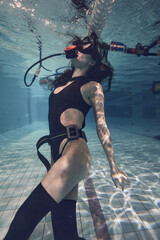 beautiful girl in a swimsuit swims in the pool in diving equipment
