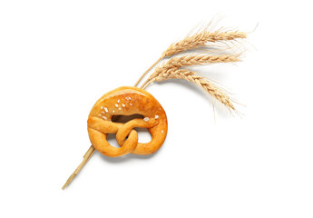 Soft pretzel and wheat spikelets on white background