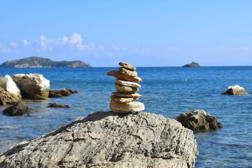 Balanced stack of rocks on a large, rough boulder on a beach on Skiathos island, Greece....