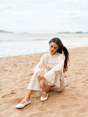 Fototapeta na wymiar Beach Beauty: Young Woman, Stylish and Attractive, Standing on the Sand, Gazing at the Ocean, Enjoying Summer Vacation.
