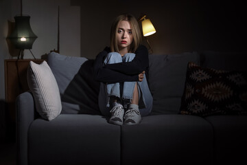 Depressed young woman in dark room at night