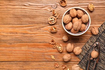 Obraz na płótnie Canvas Bowl with walnuts and nutcracker on wooden background