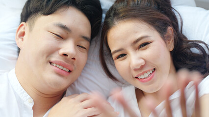 Top view young couple asia people lying down talk on bed relax smile hold hands look at ring on finger. Sweet happy lover asian man woman fall in true love new family life begin just married moment.