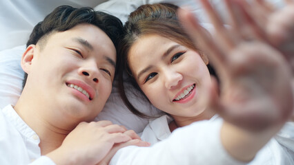 Top view young couple asia people lying down talk on bed relax smile hold hands look at ring on...