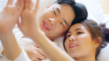 Top view young couple asia people lying down talk on bed relax smile hold hands look at ring on finger. Sweet happy lover asian man woman fall in true love new family life begin just married moment.