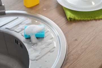 Silver sink and sponge with detergent in kitchen