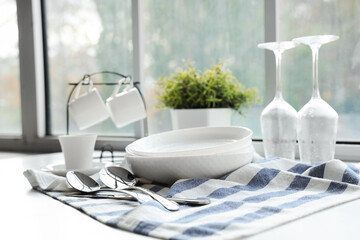 Set of clean dishes on table near window in kitchen