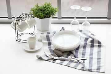 Set of clean dishes on table near window in kitchen