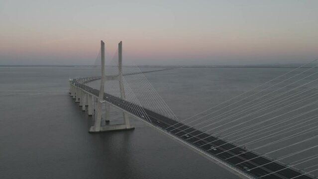Drone flyover shot of Vasco da Gama bridge over Tagus river in Lisbon, Portugal at sunset