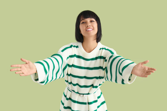 Young woman opening arms for hug on green background