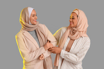 Beautiful young happy Muslim women in hijab on grey background