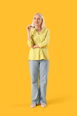 Mature woman with sunglasses on yellow background