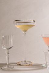 tall, thin stem champagne coupe with sherry, cocktail glasses against white with shadows	