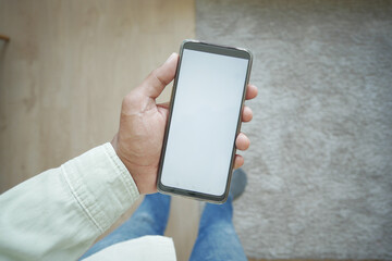 pov shot of holding smart phone with white screen at home 