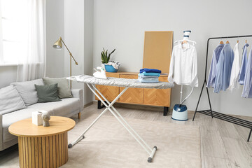 Ironing board and rack with clothes in interior of living room