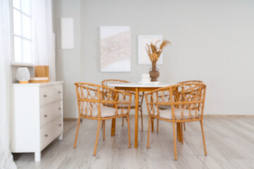 Blurred view of stylish dining room with paintings, drawers and table
