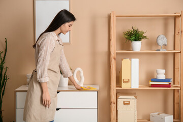 Fototapeta premium Young woman cleaning furniture in living room