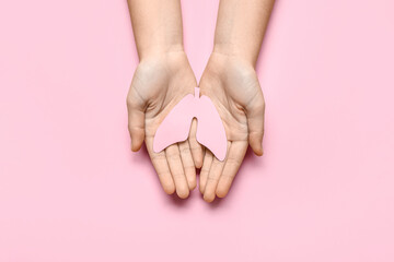 Female hands with paper lungs on pink background