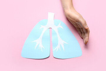 Female hand with paper lungs on pink background
