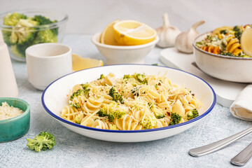 Delicious fusilli pasta with broccoli and cheese in bowl on light background, closeup