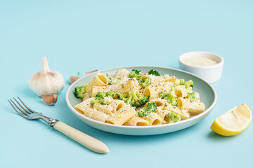 Plate of tasty pasta with broccoli on blue background