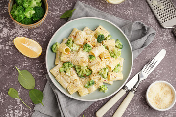 Plate of tasty pasta with broccoli on grey background