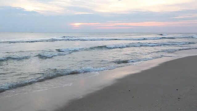 A scenic sunrise view of waves breaking along the shore of a beach in Nags Head, Outer Banks, North Carolina.