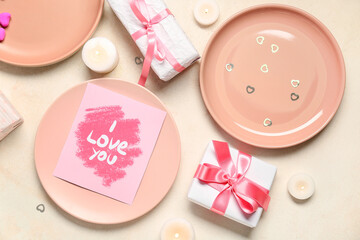 Beautiful table setting for Valentine's Day with festive card, gifts and candles on beige grunge background
