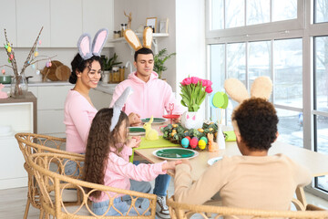 Happy family praying before dinner at table in kitchen on Easter Day