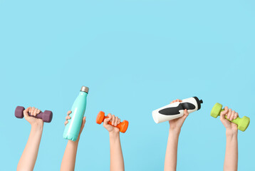 Female hands with dumbbells and bottles of water on color background
