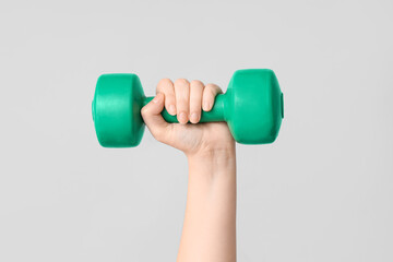 Female hand with dumbbell on grey background, closeup