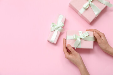 Female hands with gift boxes on pink background. International Women's Day