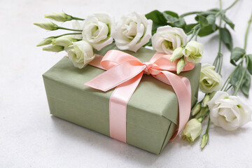 Gift box and beautiful eustoma flowers on white background. International Women's Day