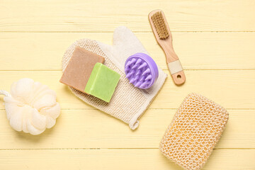 Fototapeta na wymiar Hair scalp massager with shampoo bars and bath sponges on yellow wooden background